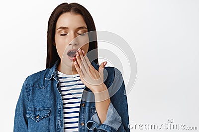 Close up of tired adult woman yawning, close eyes and cover opened mouth during yawn, feel sleepy, early in morning wake Stock Photo