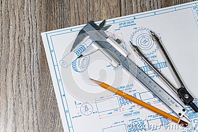 Close up to blue print, pencil, calipers, dividers laying over natural wooden background. Engineering activity and creativity. Stock Photo