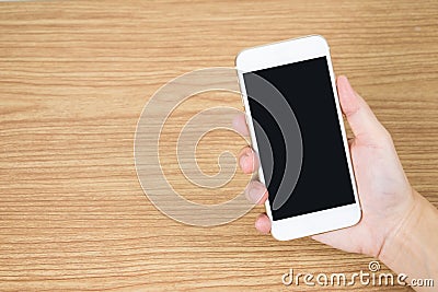 Close up to the hand holding the mobile on the old wooden table in the room Stock Photo