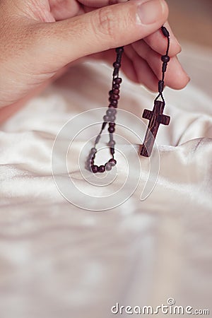 Close up to a hand holding a wooden rosary and crucifix Stock Photo