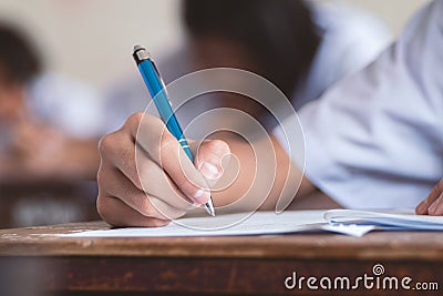 Close-up to student holding pen and writing final exam in examination room or study in classroom Stock Photo