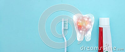 Close up of a toothbrush and toothpaste with thin linear Low poly tooth icon on blurred blue background. Oral Care Concept. Stock Photo