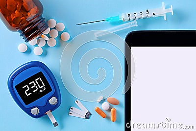 Close up top down view of glucose meter, drug pills, insulin syringe and tablet pc with blank white screen for copy space on blue Stock Photo