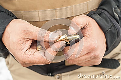 View of soldier hands load gun bullets into cartridge clip Stock Photo