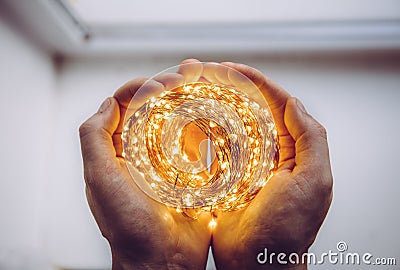 Close up top view of person holding roll of wire micro LED string lights in hands. Stock Photo