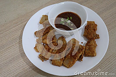 Close-up, top view, pork belly marinated in fish sauce, battered and fried with sauce placed on a plate. Stock Photo