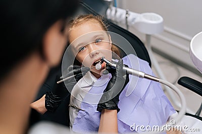 Close-up top view of unrecognizable female orthodontist examining teeth of cute little child girl with dental equipment Stock Photo
