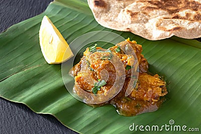 Close up traditional Indian butter chicken curry and lemon served with chapati bread on banana leaf. Stock Photo