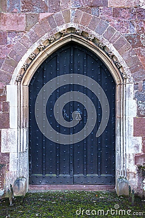 Close-up of traditional medieval wood entrance doorway with ancient brick arc in Crediton Parish Church of the Holy Cross and the Stock Photo