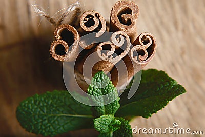 Close-up twisted sticks of cinnamon bundle, green leaves of fresh mint, selective focus, marco Stock Photo