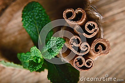 Close-up twisted sticks of cinnamon bundle, green leaves of fresh mint, selective focus, marco, set Stock Photo