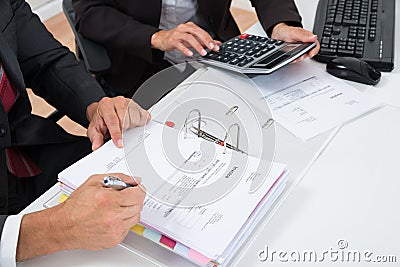 Close-up Of Two Businesspeople Calculating Invoice Stock Photo