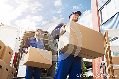 Close-up Of Two Delivery Men Carrying Cardboard Box Stock Photo