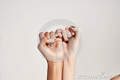 Close up of two female hands making a pinkie promise sign isolated over grey background. The symbol of commitment. Stock Photo