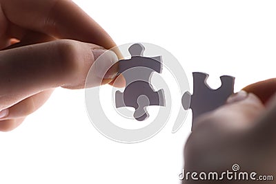 Close up of two hands trying to connect puzzle pieces. Stock Photo