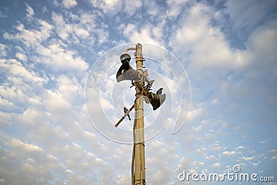 Close up of two outdoor megaphones on pole with two black birds against blue cloudy sky. Two old-looking dusty loudspeakers on the Stock Photo