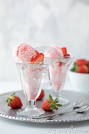 Two strawberry ice cream sundaes on a metal tray with a bowl of strawberries in behind. Stock Photo