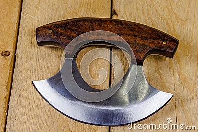 Close up of a Ulu knife with a wood handle on pine boards. Stock Photo
