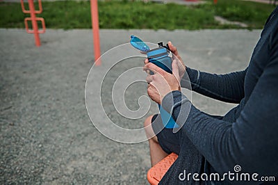 Close-up of an unrecognizable athlete holding a fresh water bottle rehydrating his body after exercise, bodybuilding and outdoor Stock Photo