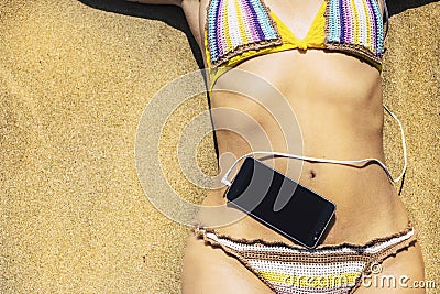 Close up of unrecognizable caucasian woman body with coloured bikini and modern phone with music cable in - concept of relax and Stock Photo