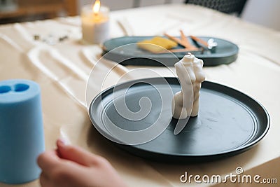 Close-up of unrecognizable female artisan putting on table ready to use handmade candle in shape of beautiful body of Stock Photo