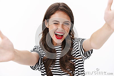 Close-up upbeat lucky alluring female stretch hands sideways, hold camera, taking selfie smiling sassy and wink Stock Photo