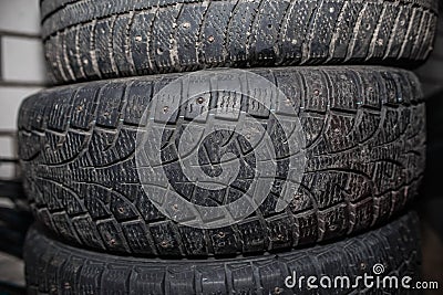 Close-up of used auto wheels folded horizontally. Discarded winter spiked car tires, worn out tread Stock Photo