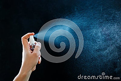 Close up of using antibacterial hand spray on black background. Stock Photo