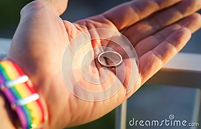close-up view of a man& x27;s hand showing a ring with an LGBT rainbow wristband. Stock Photo