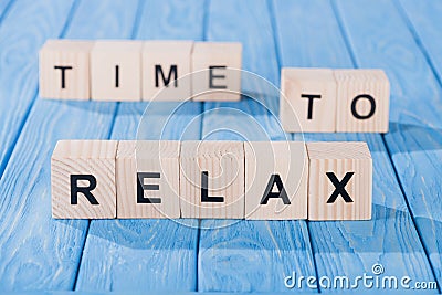 close up view of arranged wooden blocks into time to relax phrase on blue Stock Photo