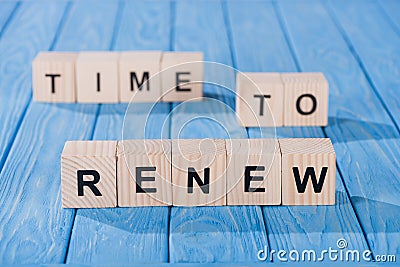 close up view of arranged wooden blocks into time to renew phrase on blue wooden surface Stock Photo