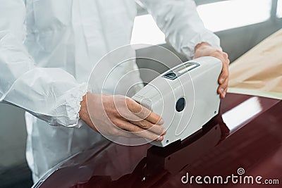 Close-up view of a auto painter determining the exact shade of a car`s color using an electronic scanner. Stock Photo