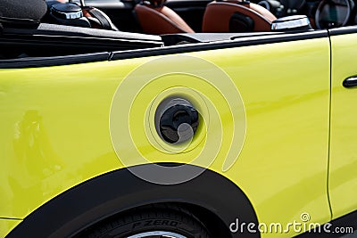 Close up view of black fuel filler cap placed on glossy yellow side of expensive sports automobile. Polished metallic Editorial Stock Photo