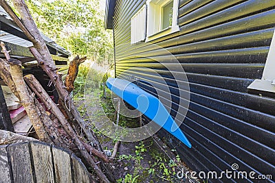 Close up view of blue kayak parked near dark house wall. Stock Photo