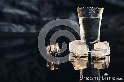 Close-up view of bottle and glasses of vodka standing isolated on black. Stock Photo