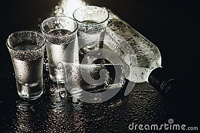 Close-up view of bottle and glasses of vodka standing isolated on black. Stock Photo