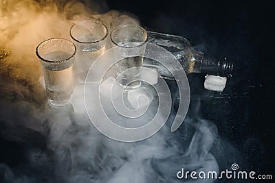 Close-up view of bottle and glasses of vodka standing isolated on black. Stock Photo