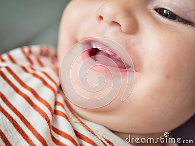 A close-up view capturing the joyful expression of a baby who is smiling and showing two little teeth. The childs eyes Stock Photo