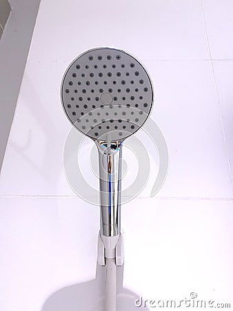 Close up view of a chrome showerhead with cheap plastic hose in a bathroom Stock Photo