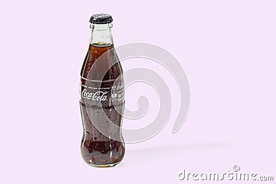 Close up view of Coca Cola in a glass bottle isolated on pink background. Editorial Stock Photo