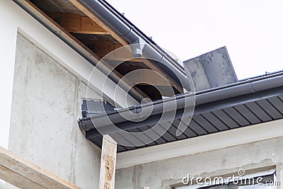 close-up view of corner of house with a gray roof and plums and filing of roof overhangs with soffits of house under construction Stock Photo