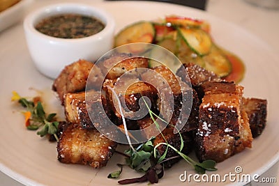 Close-up view of cubed pork belly dish with garnishes at a restaurant Stock Photo