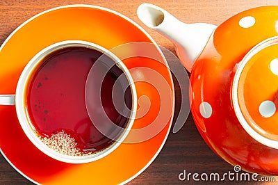 Close up view of cup with hot aromatic black tea and teapot with white polka dots on a wooden table. Tea time concept. Flat lay Stock Photo