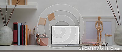 Designer home office with mock up laptop, painting tools, books and decorations on white table Stock Photo