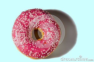 Close up view of donut sprinkled with white glaze isolated on blue background. Stock Photo