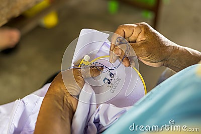 Close-up view of an elderly woman hand using a needle and blue thread to embroider Stock Photo