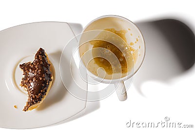 Close up view of empty cup with rest of coffee and piece of chocolate donut. . Stock Photo