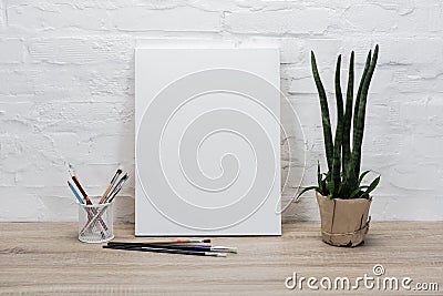 close up view of empty drawing easel, paintbrushes and plant in flowerpot Stock Photo