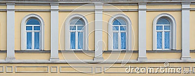 Facade of ancient yellow building with four arched windows Stock Photo