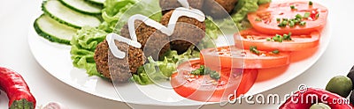 Close up view of falafel with sauce on plate with sliced vegetables on white background, panoramic shot. Stock Photo